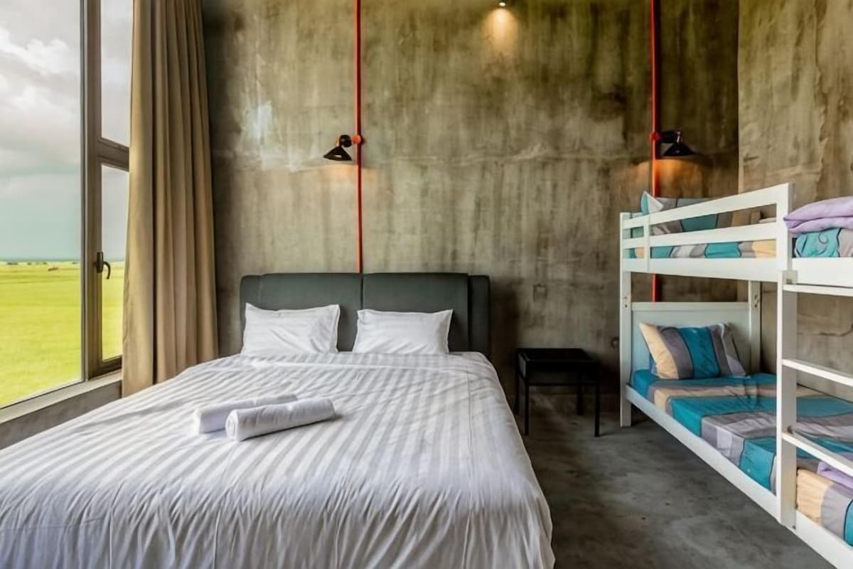 A bunk bed room with a large window, a bed with white bedding, and a concrete wall.