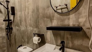 Ένα μπάνιο με τουαλέτα, νιπτήρα, καθρέφτη και κρεμάστρα για πετσέτες.