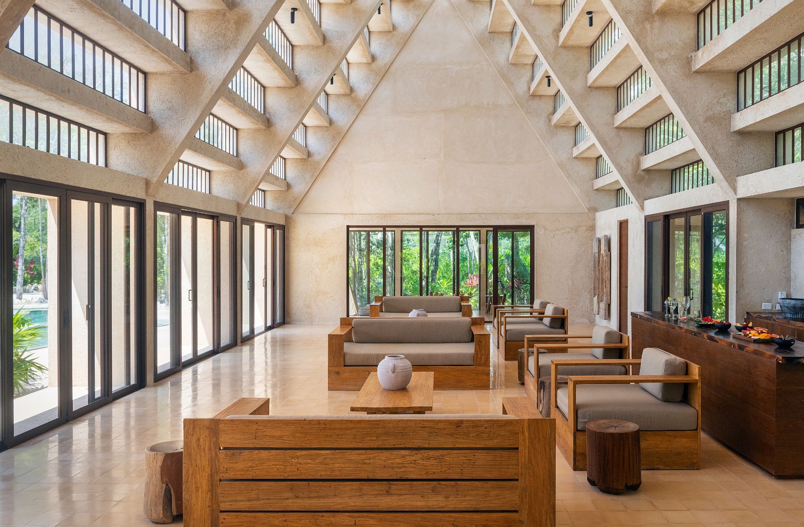 A spacious interior with a high ceiling, large windows, and a central seating area with sofas and tables.