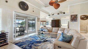 A spacious living room with a large sectional sofa, a glass coffee table, and a blue patterned rug.