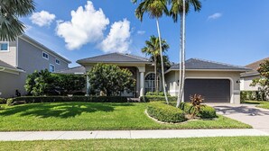 A residential area with houses featuring a similar architectural style, well-maintained lawns, and palm trees.
