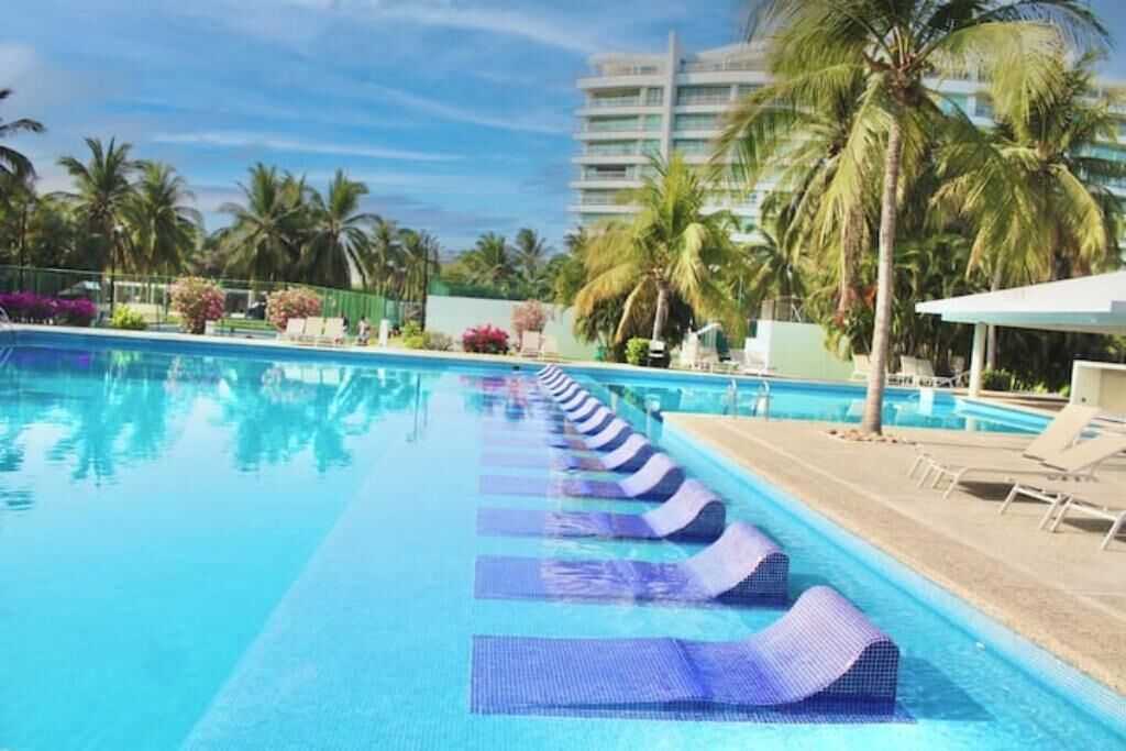 Ein Schwimmbecken mit Liegestühlen und Palmen.