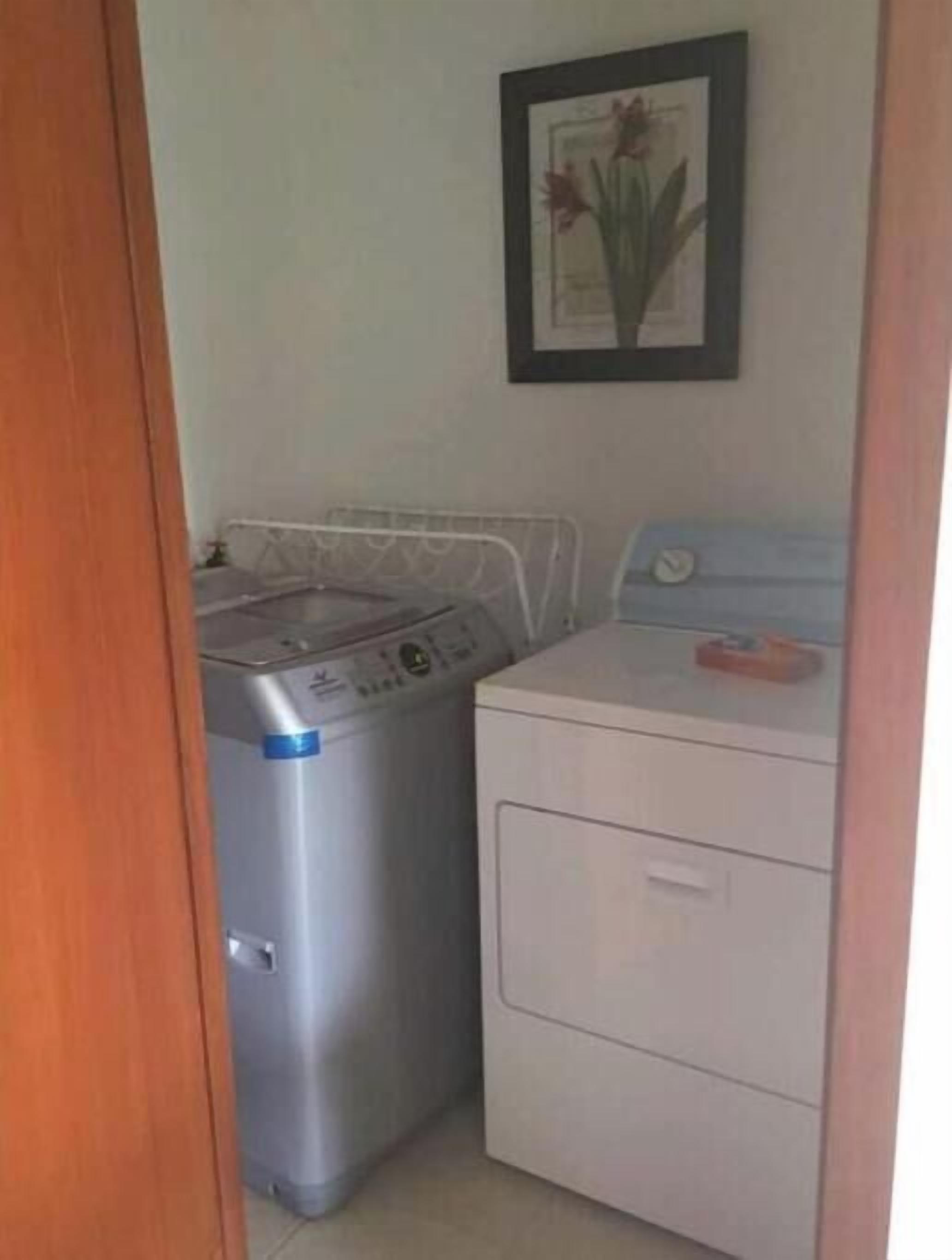 Ein Waschraum mit Waschmaschine und Trockner, einem gerahmten Bild an der Wand und einer Holztür.