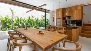 A modern kitchen with wooden cabinets, a central island, and a dining area with a wooden table and chairs.