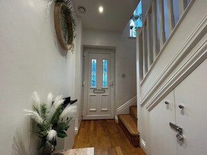 A hallway with a wooden floor, a white door with glass panels, and a staircase with white railings. - Secure 2BD Retreat: Modern Comfort in Privacy (Medway)