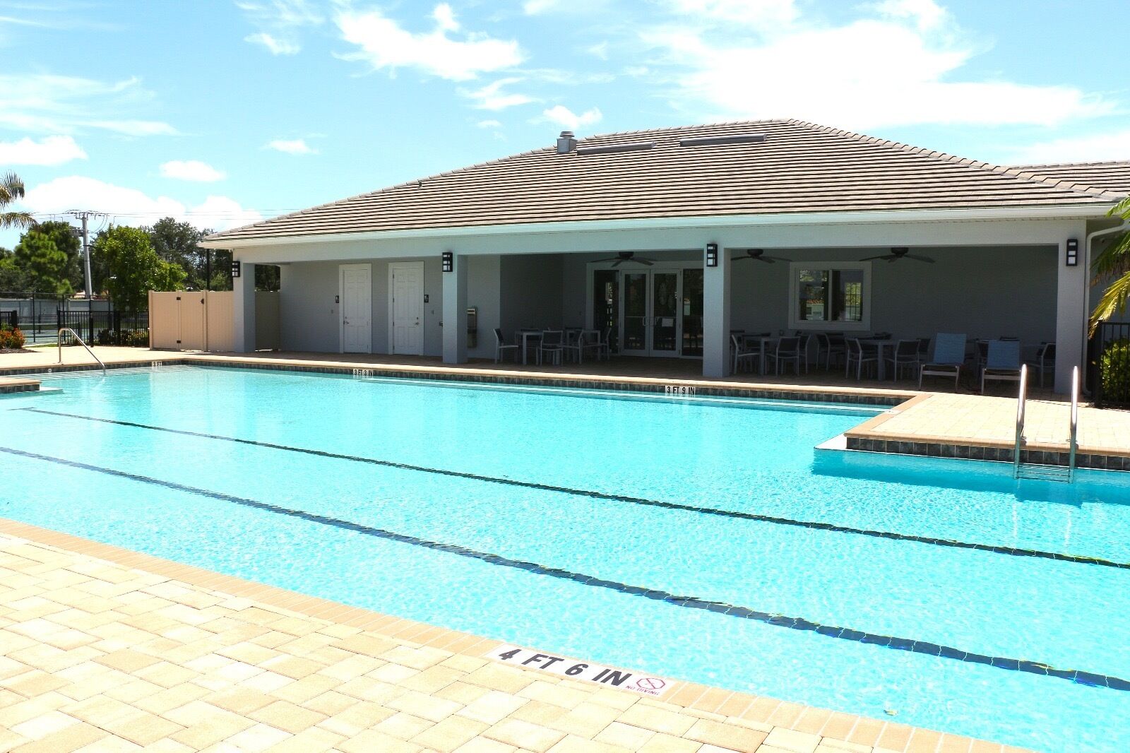 A rectangular swimming pool with clear blue water, surrounded by a tiled deck.