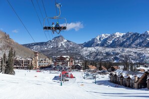 A ski resort with a chairlift, snow-covered mountains, and lodge buildings.