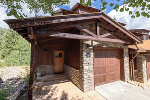A rustic cabin with a stone facade, wooden exterior, and a covered porch.