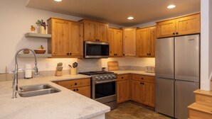 A modern kitchen with wooden cabinets, stainless steel appliances, and a granite countertop.