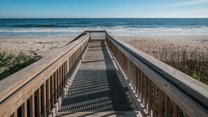 A wooden boardwalk leading to a beach with the ocean in the background. - New listing! Direct oceanfront 2/2 with private balcony, heated pool, and hot tub (New Smyrna Beach)