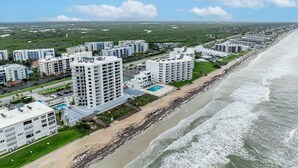 A coastal residential area with high-rise buildings, a beach, and a clear sky. - New listing! Direct oceanfront 2/2 with private balcony, heated pool, and hot tub (New Smyrna Beach)