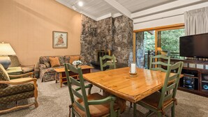 A cozy living room with a stone fireplace, wooden dining table, and comfortable seating. - Stonebridge Condos Unit 723 (Snowmass Village)