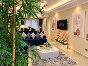 A modern living room with a blue sofa, a coffee table, and a TV displaying 'NETFLIX'. - Casa De Horyea 2 - الميرغني (Cairo Governorate)