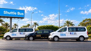 Three vehicles with '19970' and 'CAT AIRPORT TRAVEL' on them, parked in front of a 'Shuttle Bus' sign.