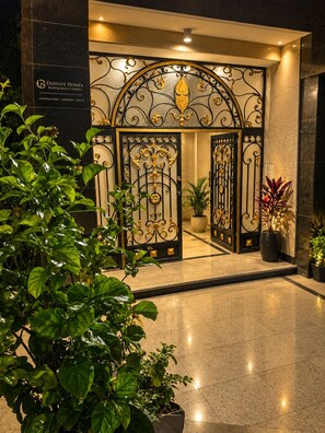 A hotel entrance with a wrought iron gate, potted plants, and a sign for Destiny Homes.