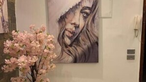 A modern interior with a large abstract painting on the wall, a potted plant with pink flowers, and a stone wall on the left. - Casa De Horyea 2 - الميرغني (Cairo Governorate)