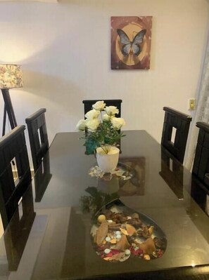 A dining table with a centerpiece of white flowers and a small plant, surrounded by black chairs.