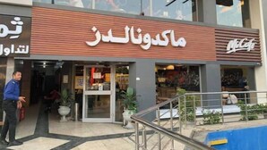 A modern building with a McCafe sign, a McDonald's logo, and a sign with Arabic text. - Casa De Horyea 2 - الميرغني (Cairo Governorate)
