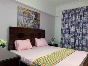 A hotel room with a bed, a nightstand, a painting on the wall, and a window with curtains.
