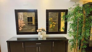 A dark wooden cabinet with three doors, a vase with flowers, and two framed mirrors on the wall above. - Casa De Horyea 2 - الميرغني (Cairo Governorate)