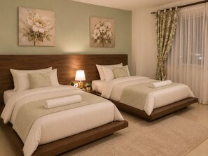 Ein Hotelzimmer mit zwei Betten, einem hölzernen Kopfteil, einem Nachttisch mit Lampe und floralen Bildern an den Wänden.