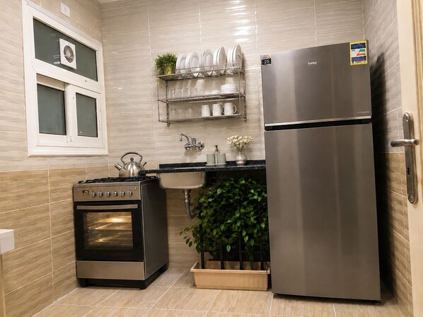 A compact kitchen with a stainless steel refrigerator, a built-in oven, and a sink.