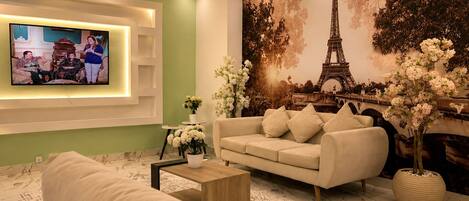 A living room with a sofa, coffee table, and a TV mounted on the wall.