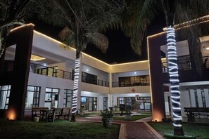 A multi-story building with outdoor seating and a well-lit entrance. - LOU WAI LOU MANSIONS (Harare)