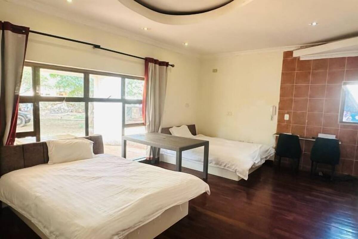 A hotel room with a large bed, a smaller bed, a desk, and a chair.