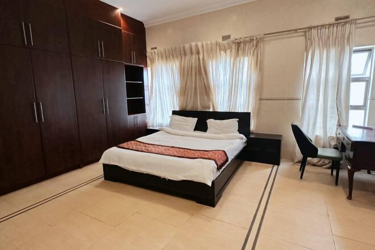 A bedroom with a bed, a desk, and a wardrobe.