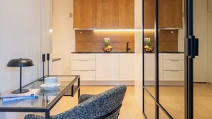 A modern kitchen with wooden cabinets, a glass dining table, and a sofa. - Stylish Flat with Workspace & Garage by HostWise (Porto)