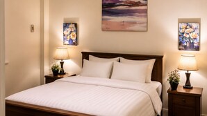 Une chambre à coucher avec un lit en bois, deux tables de chevet avec des lampes, un luminaire au plafond et deux tableaux encadrés accrochés au mur.