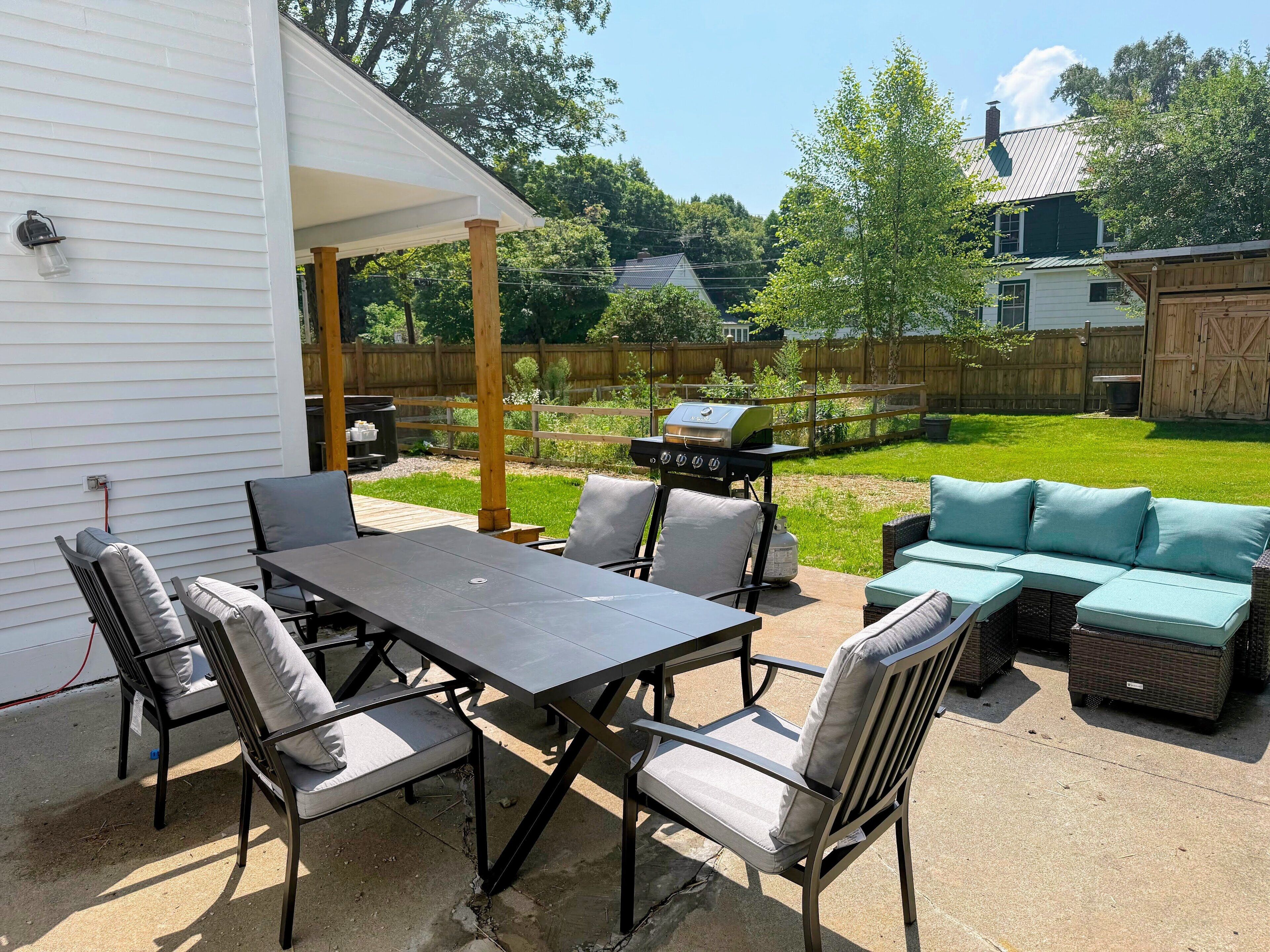 A patio with a table and chairs, a grill, and a sofa.