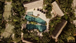 Eine Vogelperspektive zeigt ein Anwesen mit Schwimmbad, Tennisplatz und einer überdachten Terrasse.
