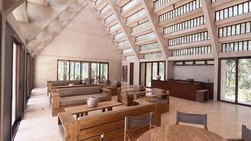Un interior espacioso con techos altos, ventanas amplias y un diseño moderno que incluye muebles de madera y una mesa redonda central.