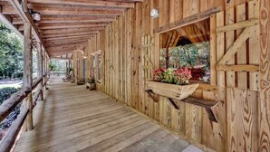 Ein gedeckter Holzsteg im rustikalen Stil, mit einer Bank und einem Fenster mit Blick auf Grünflächen.