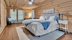 Ein Schlafzimmer mit einem großen Bett, Holzwänden, einem Deckenventilator und einem Nachttisch mit Lampe.