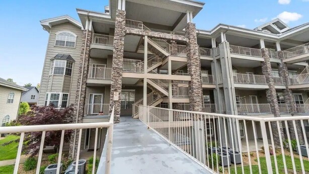 Un edificio residencial de varios pisos con una escalera central, balcones y un corredor cubierto.