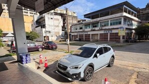Un SUV bianco parcheggiato sotto una tettoia con un edificio sullo sfondo.