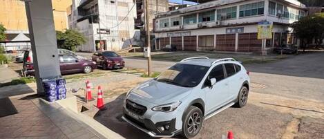 Un SUV blanco estacionado en una gasolinera, con un edificio al fondo.