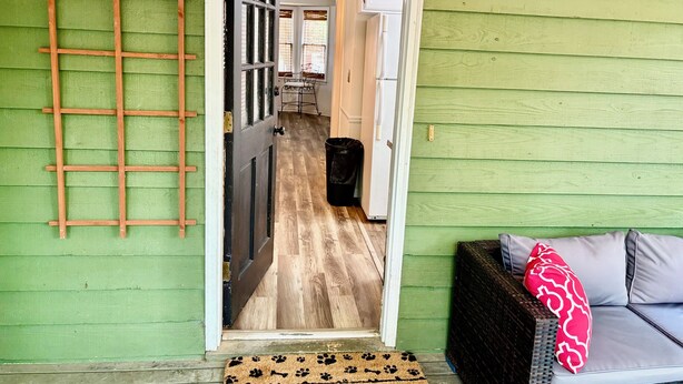 A doorway leading into a room with a wooden floor, a black door, and a green wall.