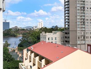 A high-rise building with a red roof, surrounded by other buildings and a body of water.