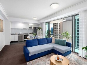 A modern living room with a sectional sofa, a coffee table, and a kitchen in the background.
