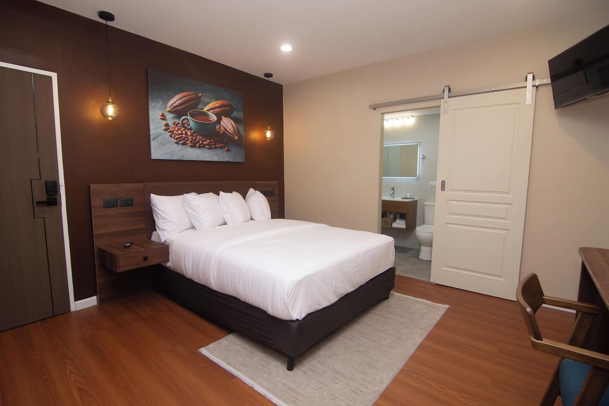 A bedroom with a bed, nightstand, and a painting on the wall.