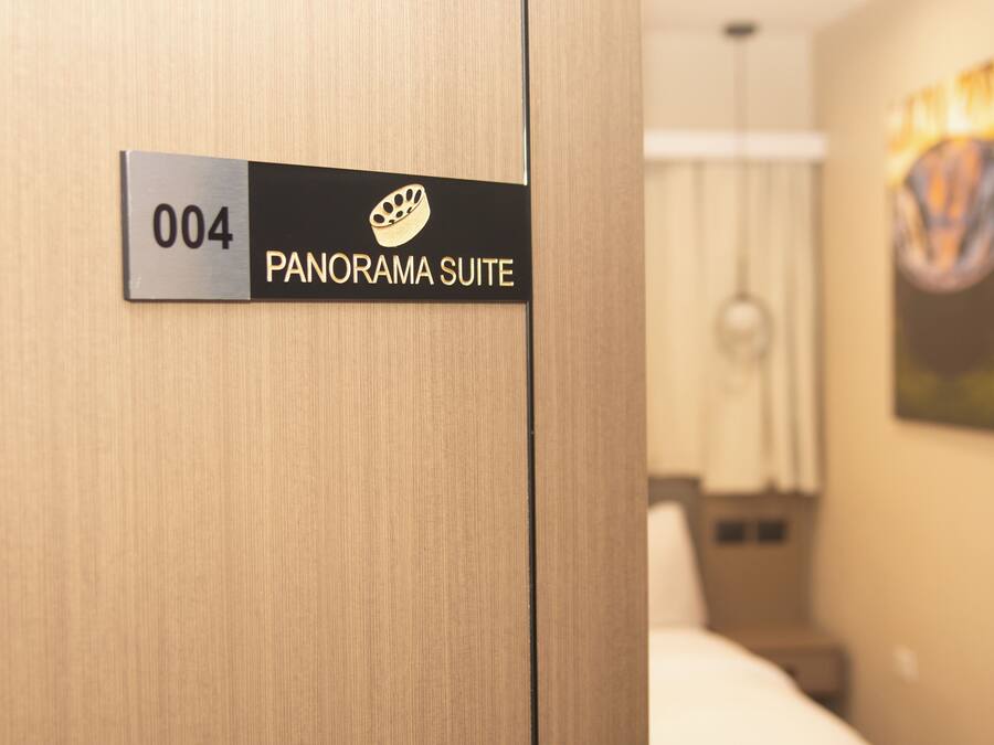 A hotel room with a sign indicating '004 PANORAMA SUITE.'