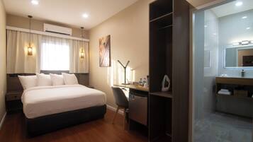 Ein Hotelzimmer mit Bett, Schreibtisch, Stuhl und Spiegel.