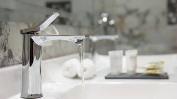 Un baño moderno con grifería de cromo y pared cubierta de mármol.