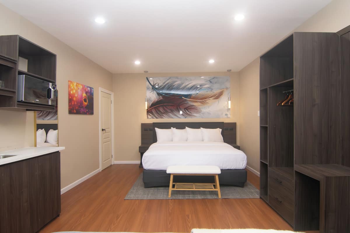 A modern bedroom with a large bed, built-in wardrobe, and a painting on the wall.