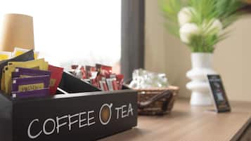 Un dispensador de café y té sobre una mesa de madera, con una ventana al fondo.