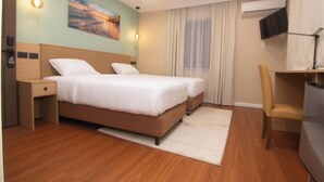 A modern hotel room with a large bed, a desk, a chair, and a TV. - Tstays Smart Hotel (Port of Spain)